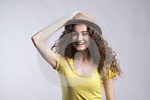 Portrait of a gorgeous teenage girl with curly hair and hat. Studio shot, white background with copy space