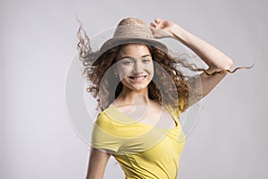Portrait of a gorgeous teenage girl with curly hair and hat. Studio shot, white background with copy space