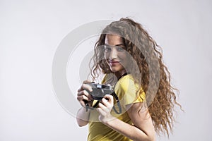 Portrait of a gorgeous teenage girl with curly hair holding camera. Studio shot, white background with copy space