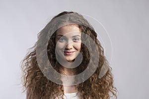 Portrait of a gorgeous teenage girl with curly hair. Studio shot, white background with copy space