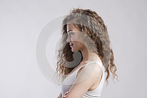 Portrait of a gorgeous teenage girl with curly hair. Studio shot, white background with copy space, side view.