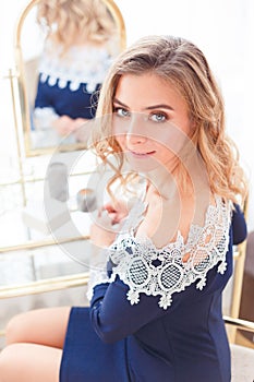 Portrait of gorgeous woman in blue dress at dressing table with mirror