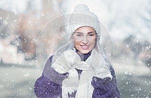 Portrait of gorgeous woman in warm clothing on snowing winter day outdoors. Snowflakes falling on cheerful girl wearing wool cap,