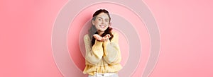 Portrait of gorgeous young woman with bright make up, holding on palms, smiling and demonstrating something in her hands