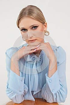 Portrait of gorgeous young woman in delicate skiey blouse and stylish earrings, white background, free copy space photo