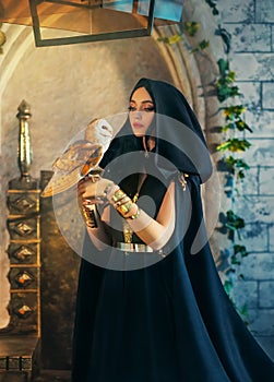 Portrait gothic fantasy halloween woman dark queen witch in black dress, cape hood on head. Girl elf princess sorceress