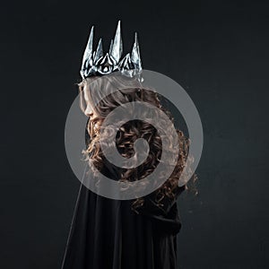 Portrait of a Gothic Princess. Beautiful young brunette woman in metal crown and black cloak. photo