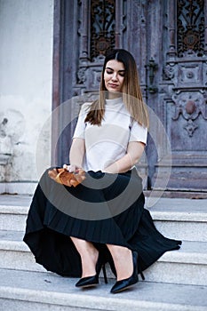 Portrait of a grace woman sitting on the stair on a grey door, as old building. Outdoors portrait in evening time day.