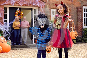 Portrait Of Grandchildren Dressing Up To Visit Grandparent's House Trick Or Treating On Halloween