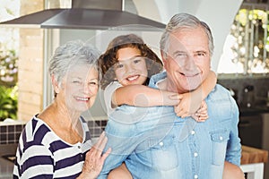 Portrait of grandfather carrying girl while standing besides grandmother