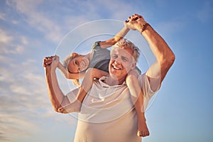 Portrait of Grandfather carrying his granddaughter on his shoulders while walking along the beach. Adorable little girl