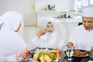 Grandmother feeding her granddaughter in dining room photo