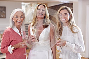 Portrait Of Grandmother With Adult Daughter And Granddaughter Trying On Wedding Dress In Store