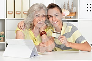 Portrait of grandmother and boy using modern laptop shopping online