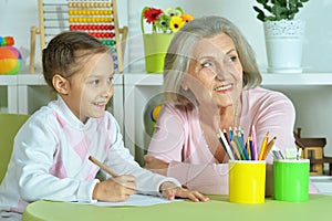 Portrait of grandmother with granddaughter drawing at home