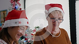 Portrait of grandmother with granddaughter wearing santa hats