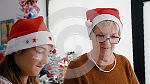 Portrait of grandmother with granddaughter wearing santa hats