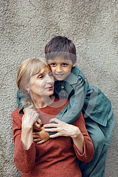 portrait of a grandmother and grandson against a gray wall on street