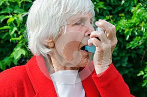 Portrait of grandmother have asthma, allergy attack outdoors. caucasian granny use aerosol, spray with drug, medicine