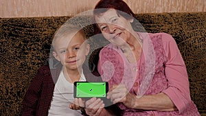 Portrait of a grandmother and her grandson with a green-screen phone.