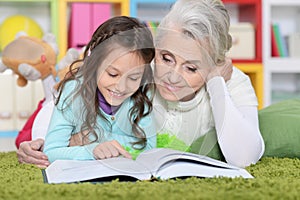 Portrait of grandmother reading book with granddaughter