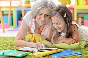 Grandmother reading book with her little granddaughter photo