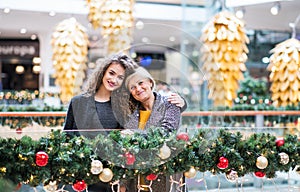 A portrait of grandmother and teenage granddaughter in shopping center at Christmas.