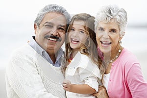 Portrait Of Grandparents On Beach With Granddaughter