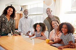 Portrait Of Grandparents Sitting At Table With Grandchildren Playing Games On Family Visit