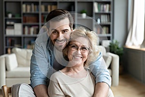 Portrait of grateful adult son hugging senior mother