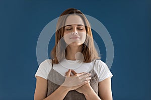 Portrait of grateful hopeful woman holding hands on chest isolated