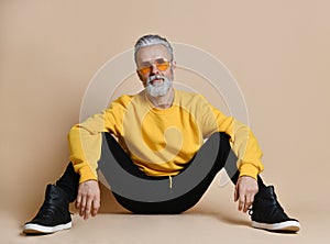Portrait of gray hair senior millionaire man in yellow sunglasses pointing fingers up photo