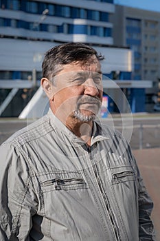 Portrait of a gray-haired 70-year-old man with a beard and mustache. A confident, serious man against the background of