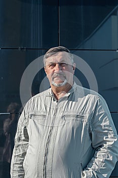 Portrait of a gray-haired 70-year-old man with a beard and mustache. A confident, serious man against the background of