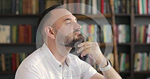 Portrait of a graying man entrepreneur, professor on bookshelves background.