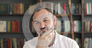 Portrait of a graying man University Professor in the library looking at camera.