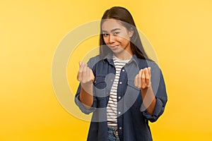 Portrait of greedy girl in denim shirt showing money gesture and looking with cunning smile, planning big profit