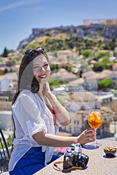 Portrait of a Greek girl enjoying a drink overlooking the Acropolis of Athens
