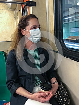 Portrait of a greek woman sitting in the metro - subway of Athens wearing surgical mask.