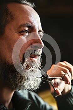 Portrait of a grey bearded man with a scissors, routine treatment for cutting and grooming