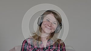 Portrait of grey-eyed Caucasian girl in headphones smiling and laughing at camera. Cheerful young woman with golden hair