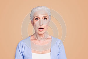 Portrait of grey haired old nice beautiful amazed shocked woman. Isolated over violet purple background