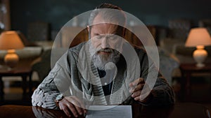 Portrait greyhaired gentleman signing contract indoors. Man reading documents.