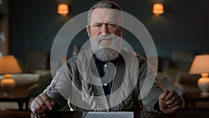 Portrait greyhaired gentleman signing contract indoors. Man reading documents.