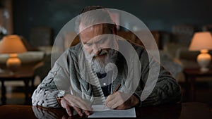 Portrait greyhaired gentleman signing contract indoors. Man reading documents.