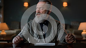 Portrait greyhaired gentleman signing contract indoors. Man reading documents.