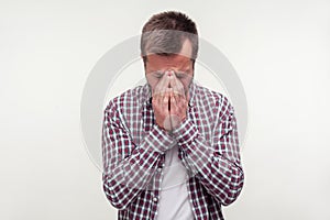 Portrait of grieving bearded man hiding face in hands and crying, feeling sorrow. white background