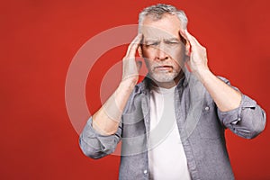 Portrait of a groggy upset worried sad, depressed, tired senior man with a headache, very stressed, isolated on red background, photo