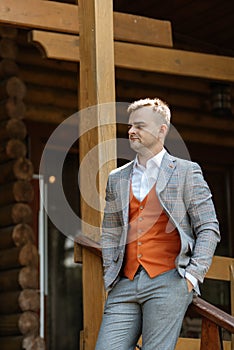 portrait of the groom in a gray suit and an orange vest