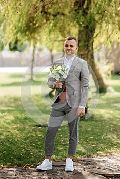 portrait of the groom in a gray suit and an orange vest